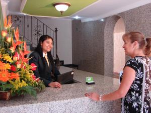 波哥大的住宿－Hotel Castellana Inn，站在柜台跟另一位女人说话的女人
