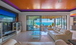 a living room with a couch and a flat screen tv at Villa Jacuzzi Seaview Villa in Chaweng Noi Beach