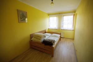シュツァブニツァにあるApartament EPI Szczawnicaのベッドルーム1室(黄色い壁のベッド1台、窓2つ付)