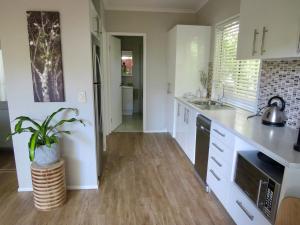 a kitchen with white cabinets and a potted plant at Beach Cottage on Cassia Avenue, Central Coolum Beach in Coolum Beach