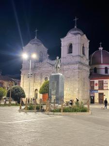 a church with a statue in front of a building at Suite Hotel Olimpico in Huancayo