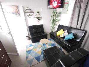 sala de estar con sofá negro y taburete en Cómodo y bonito departamento, en Santa Rosa