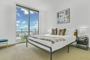 Dormitorio blanco con cama y ventana grande en Modern Luxury 2 Bed with Panoramic City Views in Downtown LA, en Los Ángeles