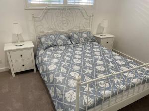 a bed with a blue and white comforter and two night stands at The White House in Bunbury