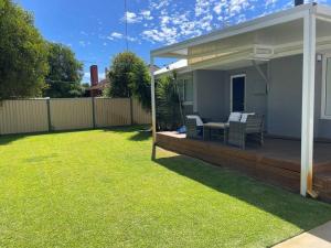 a backyard with a deck with a table and chairs at The White House in Bunbury