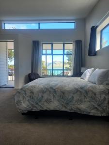 a bedroom with a bed and a large window at Taimana Boutique Motel in Diamond Harbour
