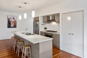 a kitchen with white cabinets and a kitchen island with bar stools at Kalima Retreat - The Ultimate Uncomplicated & Relaxing Holiday! in Dunsborough