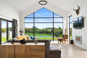 uma sala de estar com um sofá e uma grande janela em Sandhill Beach House - Te Horo Holiday Home em Te Horo