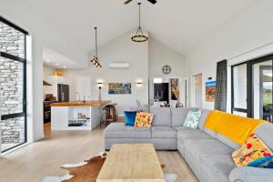 uma sala de estar com um sofá e uma mesa em Sandhill Beach House - Te Horo Holiday Home em Te Horo