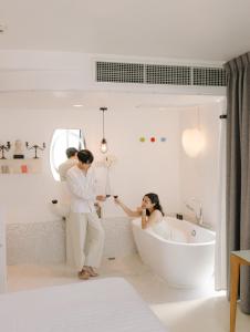 a woman standing in a bath tub in a bathroom at Art Mai Gallery Nimman Hotel Chiang Mai - SHA Plus in Chiang Mai