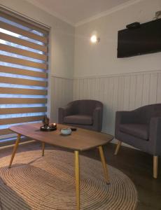 a living room with a coffee table and two chairs at Parque suizo, Pucon in Pucón