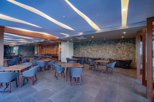 a restaurant with tables and chairs and a stone wall at Dafam Resort Belitung in Tanjungbinga