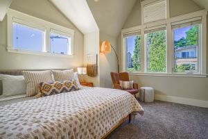 um quarto com uma cama, uma cadeira e janelas em Exquisite Central Townhome with Spacious Loft and Gourmet Kitchen em Seattle