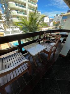 two benches and a table on a balcony with a building at Flamingo Beach Pousada in Cabo Frio