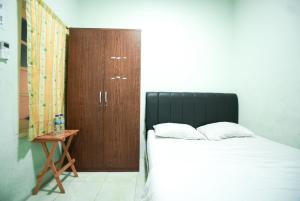 1 dormitorio con 1 cama y armario de madera en Mahkota Sivali near Soekarno Hatta Airport Mitra RedDoorz, en Tangerang