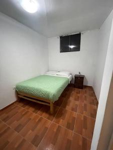 a small bedroom with a bed and a wooden floor at Departamento con vista panoramica in Cusco
