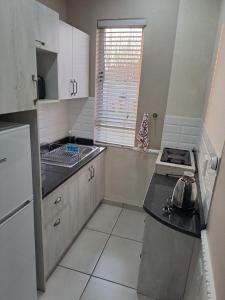 a kitchen with a sink and a stove in it at Berlydai Guest Accomodation in Secunda