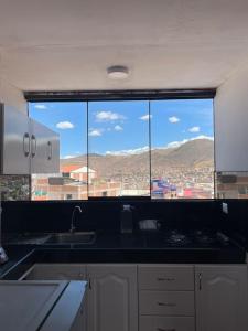 a kitchen with a view of a city from a window at Departamento con vista panoramica in Cusco