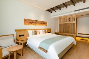 sypialnia z dużym białym łóżkiem i krzesłem w obiekcie Yoba Boutique Hotel w mieście Zhangjiajie
