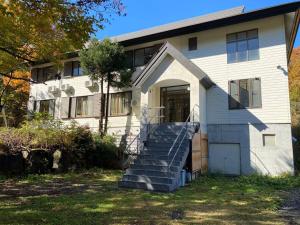 a white house with stairs in front of it at ラルパレット白馬 in Hakuba