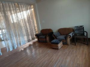 a living room with two chairs and a couch at OYO The Blue Sky Hotel And Resort in Gwalior