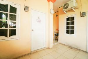 a hallway with a white door and a clock on the wall at Mahkota Sivali near Soekarno Hatta Airport Mitra RedDoorz in Tangerang