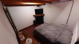 um pequeno quarto com uma cama e uma televisão em Loft Salta em Bahía Blanca