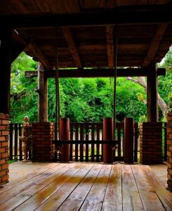 a porch with a wooden deck with trees in the background at Plei Homestay & Café in Pleiku