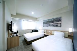 a hotel room with two beds and a television at Travelodge Kyoto Shijo Kawaramachi in Kyoto