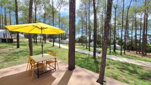 a table and chairs under a yellow umbrella on a deck at Romdoul Kirirom Resort in Kampong Speu