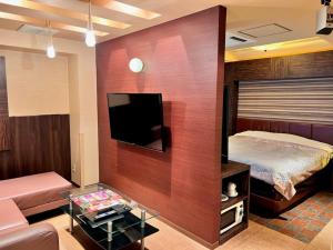 a room with a bed and a tv and a couch at Hotel Opus -Adult only- in Kasugai