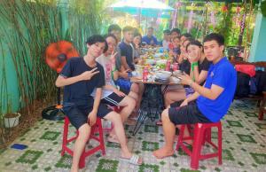 een groep mensen die aan een tafel zitten bij Quy Phuong - Homestay in Tân Hiệp