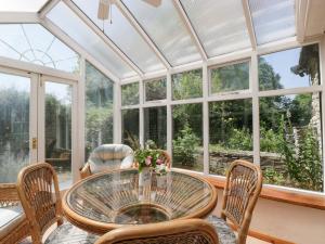 un salón acristalado con mesa de cristal y sillas en Lower Court Byre, en Kinsham