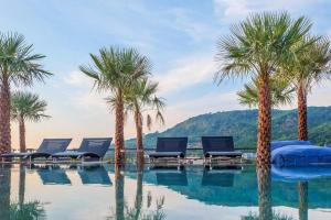 a swimming pool with palm trees and lounge chairs at Tropics Kamala 2BR Apartment CTG B605-6 in Kamala Beach