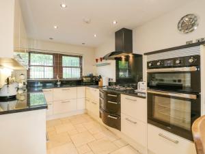 a large kitchen with white cabinets and black appliances at Torestyn in Matlock