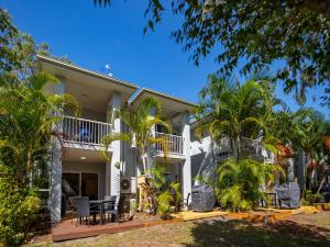 a white house with palm trees in front of it at NRMA Treasure Island Holiday Resort in Gold Coast