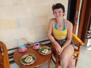 une femme assise à une table avec une assiette de nourriture dans l'établissement Bali Livin,tayehomestay, à Banjarangkan