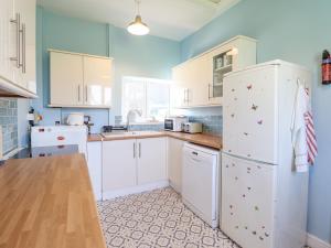 a kitchen with white cabinets and a refrigerator at Dyffryn Bach in Rug