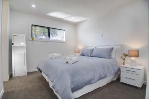 a white bedroom with a large bed and a window at Twin Camellias in Rotorua