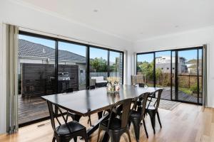 una sala da pranzo con tavolo, sedie e ampie finestre di DashAway Inverloch a Inverloch