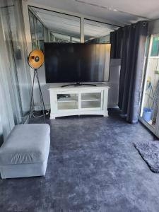 una sala de estar con TV y un centro de entretenimiento blanco en Grand t2 vue mer en La Ciotat
