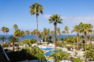 uma vista para um resort com palmeiras e uma piscina em 220 TROPICAL DUQUE Paradise by Sunkeyrents em Adeje