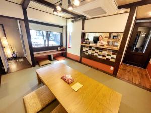 a room with a table and a woman in a counter at Guest House Pongyi in Kanazawa