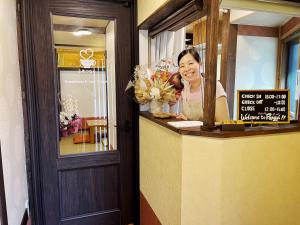 a woman is smiling behind a counter in a restaurant at Guest House Pongyi in Kanazawa