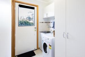 a white laundry room with a washer and dryer at JoY's Guesthouse in Romsey