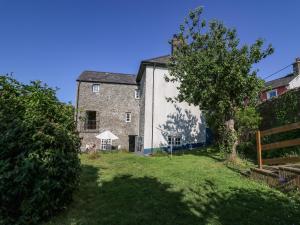 an old stone building with a tree in the yard at Dewi Villa in Aberaeron