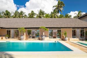 パジェにあるPaje Beach Apartments & Hotelのヤシの木が茂る家の前のスイミングプール