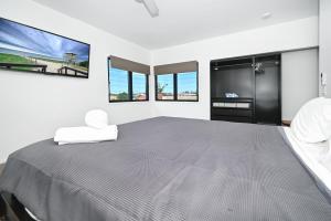 a bedroom with a large bed with two windows at Stylish Beach Side Gem - pool, beach ZG7 in Kawana Waters +17 photos