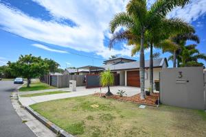 a house with palm trees in front of a street at Stylish Beach Side Gem - pool, beach ZG7 in Kawana Waters