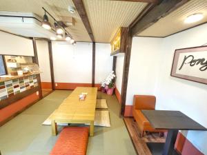 a room with two tables and benches in a restaurant at Guest House Pongyi in Kanazawa